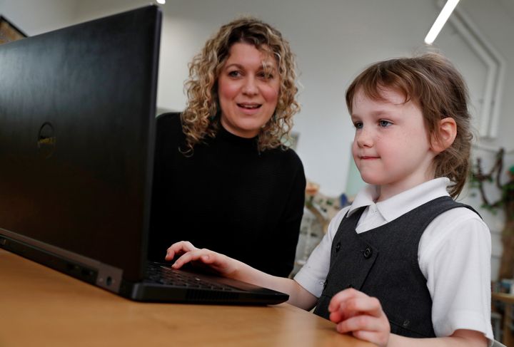 Reception class teacher Inez Horn shows five-year-old Ava Marshall how to use a laptop for home learning at Oakwood Infant school in Hartley Wintney earlier this year