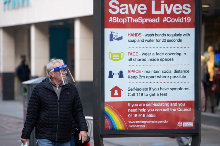 A man wearing a face shield walks past a coronavirus advice sign in Nottingham city centre. Nottinghamshire has been placed into Tier 2 of the new coronavrius restrictions with meeting socially banned indoors and the rule of six applying outdoors.