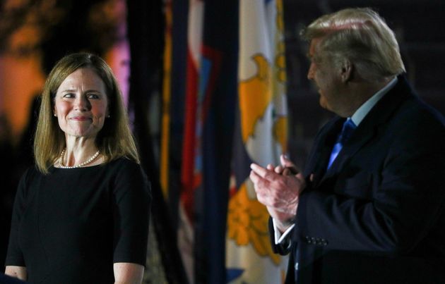 Judge Amy Coney Barrett looks over at US President Donald Trump as she is sworn in to serve as an associate justice of the Supreme Court.