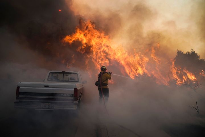 Firefighter Raymond Vasquez battles the Silverado Fire Monday, Oct. 26, 2020, in Irvine, Calif. A fast-moving wildfire forced evacuation orders for 60,000 people in Southern California on Monday as powerful winds across the state prompted power to be cut to hundreds of thousands to prevent utility equipment from sparking new blazes. (AP Photo/Jae C. Hong)