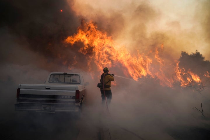 Firefighter Raymond Vasquez battles the Silverado Fire Monday, Oct. 26, 2020, in Irvine, Calif. A fast-moving wildfire forced evacuation orders for 60,000 people in Southern California on Monday as powerful winds across the state prompted power to be cut to hundreds of thousands to prevent utility equipment from sparking new blazes. (AP Photo/Jae C. Hong)