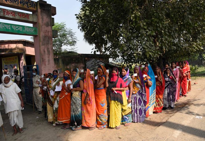 Voters stand in a queue to cast their votes outside a polling station at Paliganj in Bihar on October 28, 2020. 