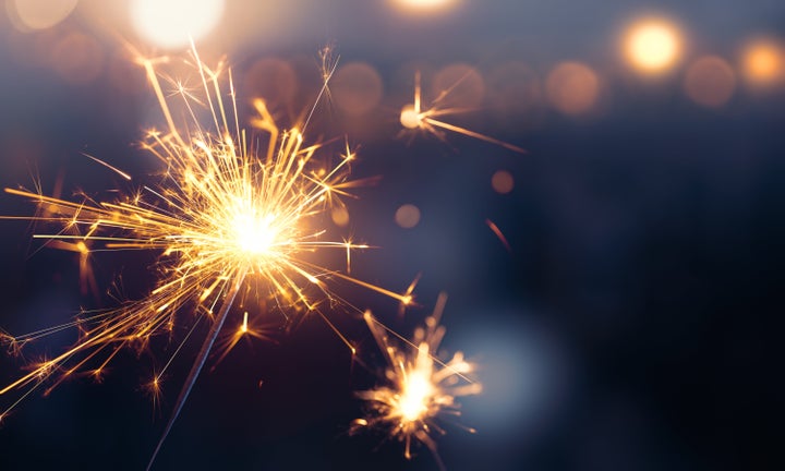 Glittering burning sparkler against blurred bokeh light background