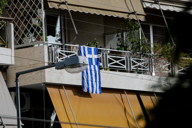 Οι σημαίες στα μπαλκόνια υπενθυμίζουν τη σπουδαιότητα της σημερινής ημέρας, παρά τις δυσκολίες της εποχής.