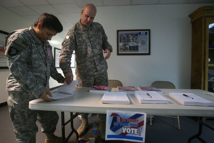 A U.S. service member (left) checks a ballot before filling it out at a U.S. military base in Afghanistan on Oct. 15, 2008. U.S. soldiers, aid workers and military contractors overseas have been allowed extra time for their ballots to arrive at election offices in the U.S.