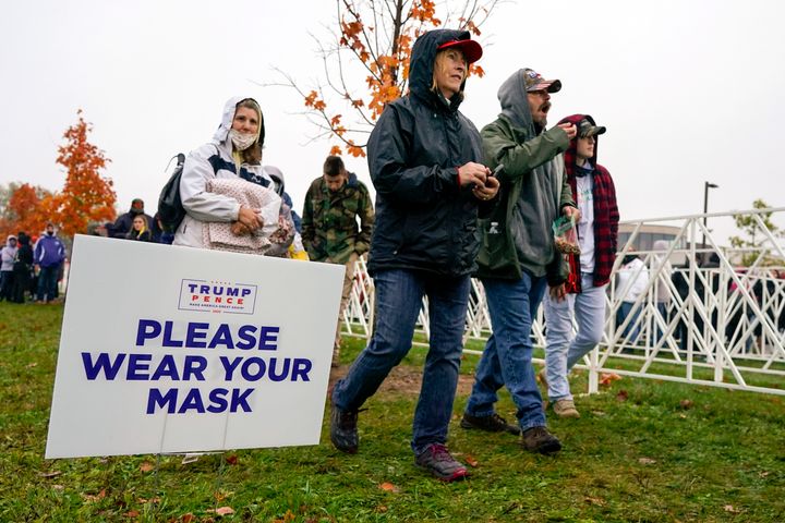 Supporters walk by a sign reminding them to wear a face mask as they arrive to hear President Donald Trump speak Monday at a campaign rally in Allentown, Pennsylvania.