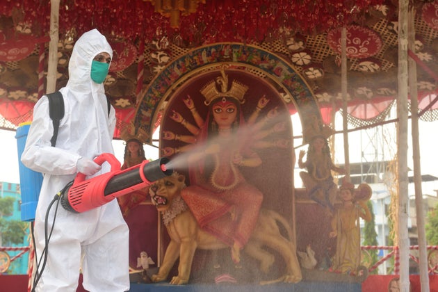 A healthcare worker is seen spraying a disinfectant inside a Durga Puja pandal in Kolkata in a file