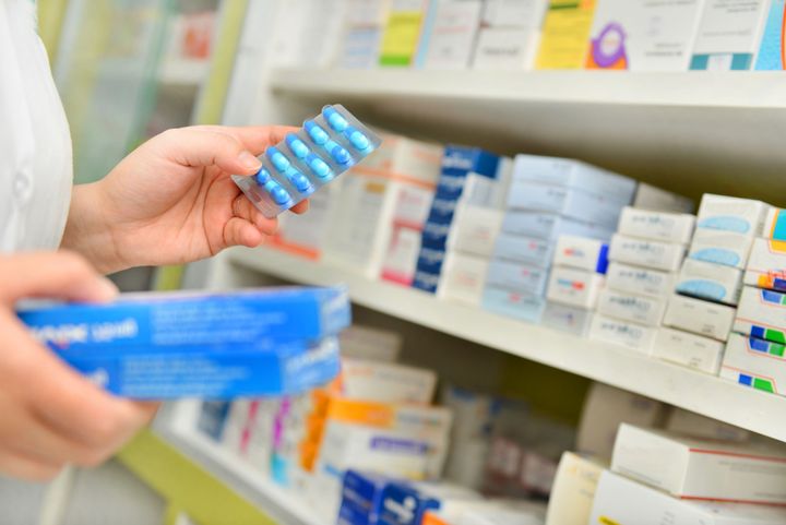 A pharmacist holds medicine box and capsule pack in a drugstore. The majority of Canadians support universal pharmacare, according to a new poll.