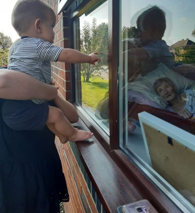 91-year-old Salina Ward gazes at grandson Levi, one, from her bed in a care home. She has not seen him in the flesh since March 