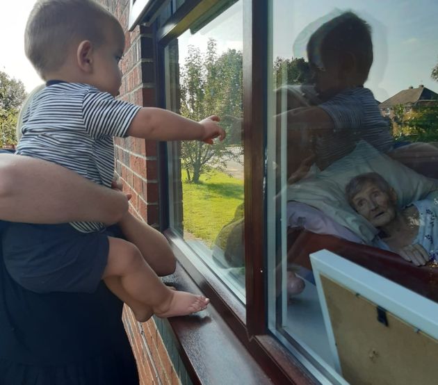 91-year-old Salina Ward gazes at grandson Levi, one, from her bed in a care home. She has not seen him in the flesh since March 