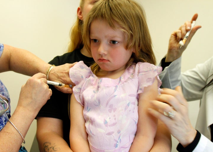 Una niña, con cara de pocos amigos mientras le vacunan