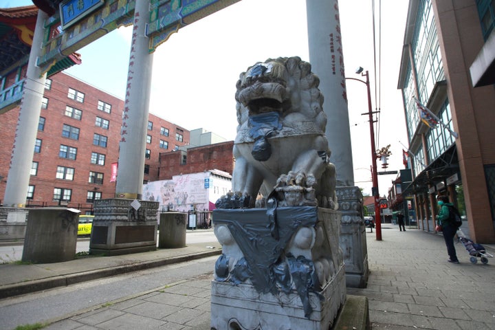 A statue is seen at the gates of Vancouver's Chinatown with racist graffiti covered, on May 21, 2020.