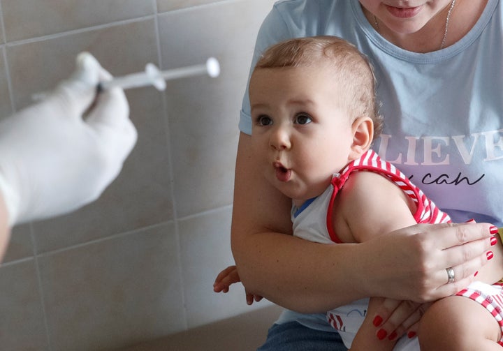 Un bebe, asustado ante una aguja con la que le van a vacunar