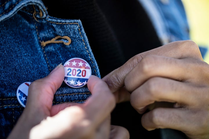 A young African American woman holding a voting badge.