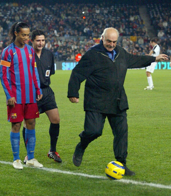 Barcelona, SPAIN: British actor Sean Connery (R) makes a ceremonial kick off with Brazilian player Ronaldinho (L) during "Match for Peace " at the Camp Nou Stadium in Barcelona, 29 November 2005. AFP PHOTO/CESAR RANGEL (Photo credit should read CESAR RANGEL/AFP via Getty Images)