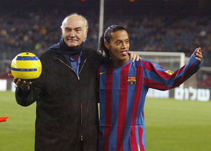 British actor Sean Connery (L) stands with Brazilian player Ronaldinho after making a ceremonial kick off during "Match for Peace " at the Camp Nou Stadium in Barcelona, 29 November 2005. AFP PHOTO/CESAR RANGEL (Photo credit should read CESAR RANGEL/AFP via Getty Images)