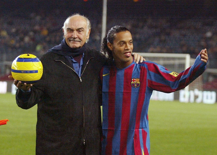 British actor Sean Connery (L) stands with Brazilian player Ronaldinho after making a ceremonial kick off during "Match for Peace " at the Camp Nou Stadium in Barcelona, 29 November 2005. AFP PHOTO/CESAR RANGEL (Photo credit should read CESAR RANGEL/AFP via Getty Images)