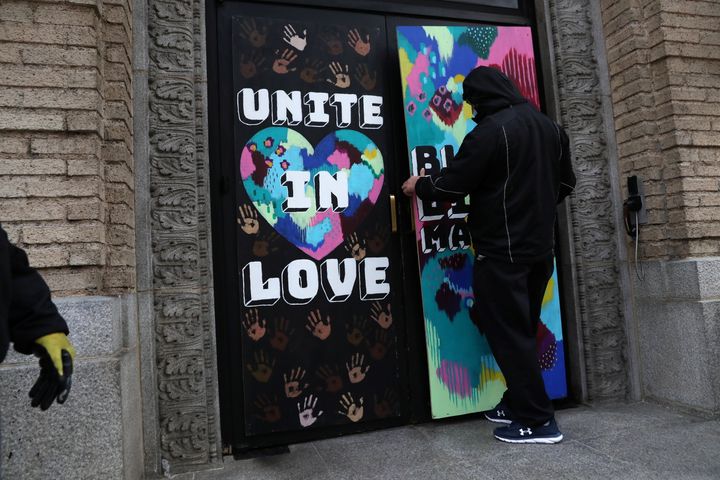 暴動警戒で窓に板をはる人。「愛で一つにまとまろう」と描かれている＝2020年10月30日、ワシントンで