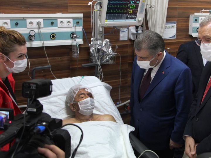 Turkey's Health Minister Fahrettin Koca, right, visits Ahmet Citim, rescued from the debris of his collapsed house, in Izmir, Turkey, Sunday, Nov. 1, 2020. (Mehmet Barlas/IHA via AP)