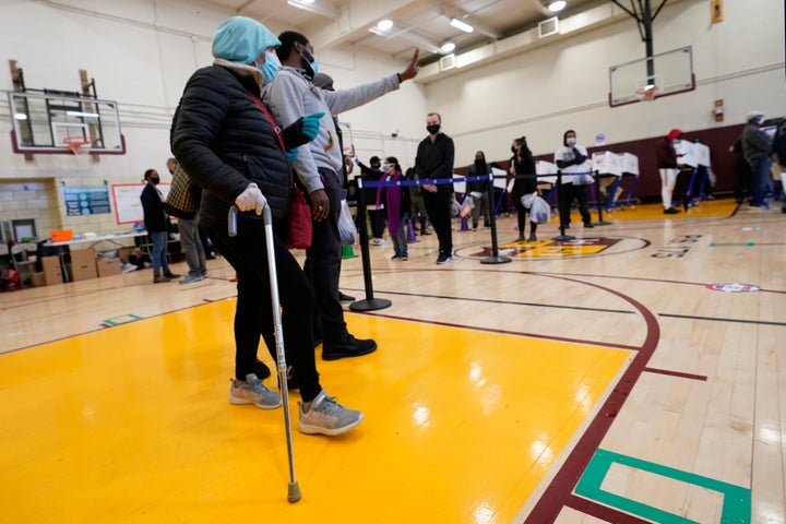 A senior citizen, left, is escorted to the head of the line, Sunday, Nov. 1, 2020, on the last day of early voting at P.S. 17