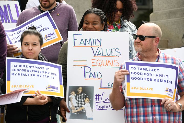Jasmine White, middle, holds up a sign alongside supporters of Senate bill 19-188 during a rally on the west steps of the State Capitol on April 9, 2019, in Denver, Colorado. During two pregnancies, White, as a single parent and sole provider for her family, had to work two jobs that didn't offer any leave. 