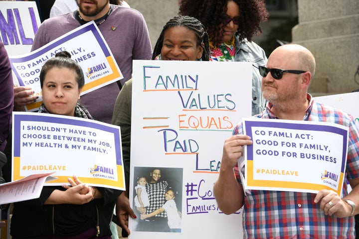 Jasmine White, middle, holds up a sign alongside supporters of Senate bill 19-188 during a rally on the west steps of the State Capitol on April 9, 2019, in Denver, Colorado. During two pregnancies, White, as a single parent and sole provider for her family, had to work two jobs that didn't offer any leave. 