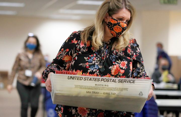 An election worker carries mail-in ballots to be processed by election workers in Salt Lake City on Oct. 29, 2020. 