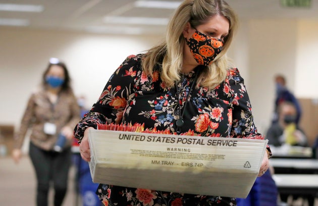 An election worker carries mail-in ballots to be processed by election workers in Salt Lake City on Oct....
