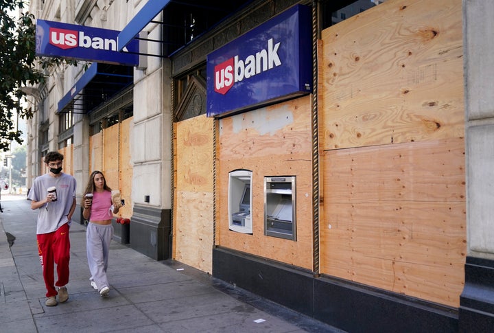 Pedestrians walk past an ATM at a boarded up US Bank branch, Monday, November 2, 2020, in downtown Los Angeles. 