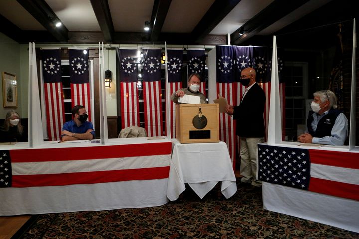Joe Casey, supervisor of the checklist, hands his ballot to town moderator Tom Tillotson to be put into a box for the US presidential election at the Hale House at Balsams Hotel in the hamlet of Dixville Notch.
