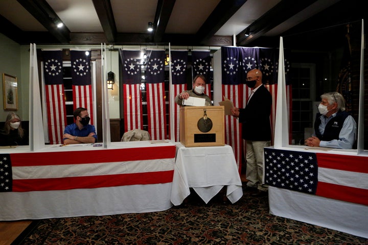 Joe Casey, supervisor of the checklist, hands his ballot to town moderator Tom Tillotson to be put into a box for the US presidential election at the Hale House at Balsams Hotel in the hamlet of Dixville Notch.