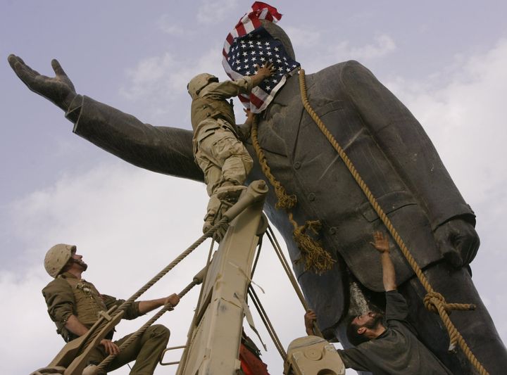 9 Απριλίου 2003 - Αμερικανοί στρατιώτες ετοιμάζονται να ρίξουν το άγαλμα του Σαντάμ Χουσέιν και καλύπτουν το πρόσωπο του με την αμερικάνικη σημαία. Ωστόσο λίγα λεπτά αργότερα απέσυραν τη σημαία και το άγαλμα γκρεμίστηκε.