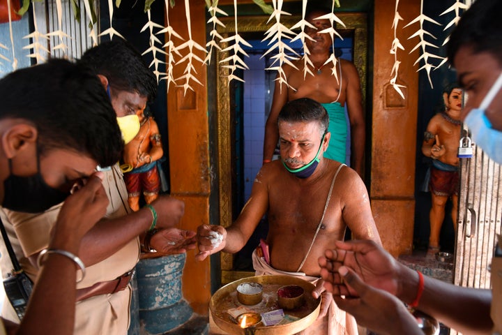 A temple priest gives holy ashes to residents as they offer prayers for the US Democratic vice-presidential candidate, Kamala Harris, at her ancestral village of Thulasendrapuram in Tamil Nadu on November 3, 2020.