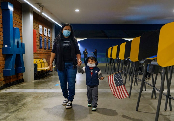 Lisa Carrera, a former Los Angeles Unified School history teacher from La Puente, Calif., holds the hand of her grandson Maverick, 2, after casting her ballot in-person at the Top of the Park at Dodger Stadium in Los Angeles, Monday, Nov. 2, 2020. (AP Photo/Damian Dovarganes)