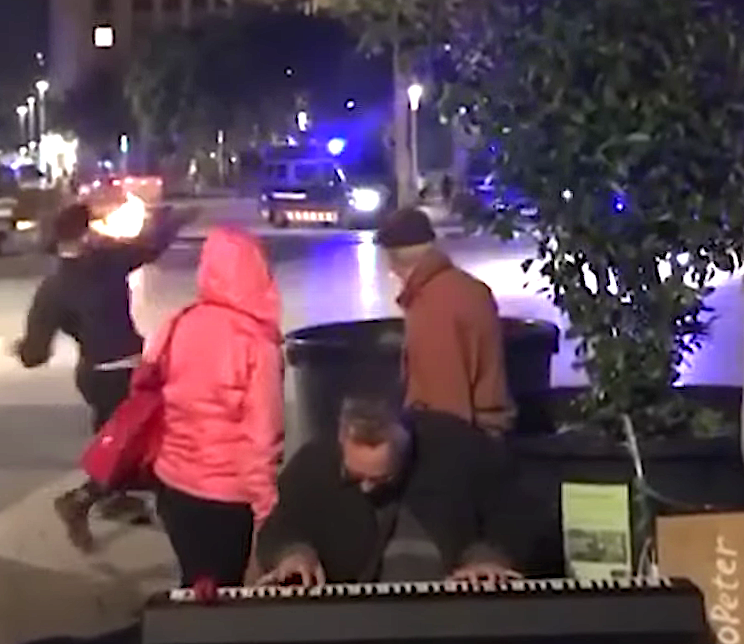 Busker Keeps Calm And Plays Keyboard As Anti-Lockdown Protest Rages Around Him