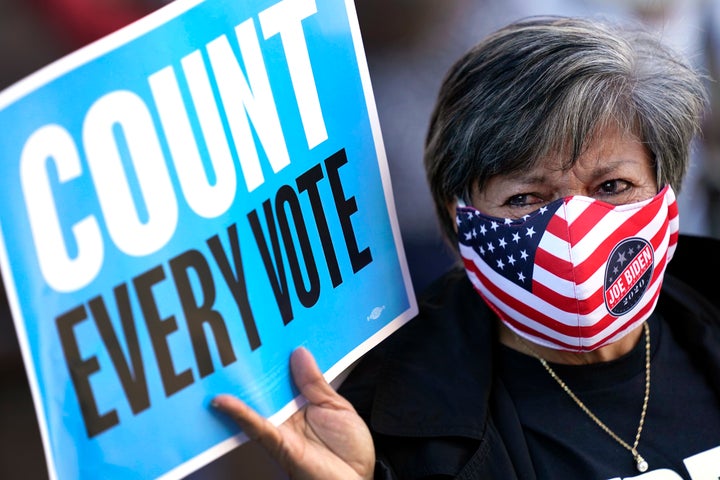 Volunteer election poll worker Cecilia Chaboudy-Dow joins demonstrators as they stand across the street from the federal courthouse in Houston, Monday, Nov. 2, 2020, before a hearing in federal court involving drive-thru ballots cast in Harris County. The lawsuit was brought by conservative Texas activists, who have railed against expanded voting access in Harris County, in an effort to invalidate nearly 127,000 votes in Houston because the ballots were cast at drive-thru polling centers established during the pandemic. (AP Photo/David J. Phillip)