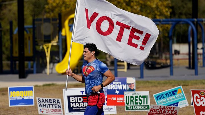 A jogger carries a "Vote" flag as he passes a polling station, Tuesday, Nov. 3, in San Antonio.