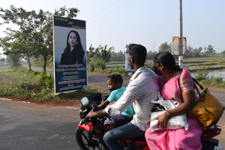 A family rides past a poster of Democratic vice presidential candidate, Kamala Harris, at her ancestral village of Thulasendr