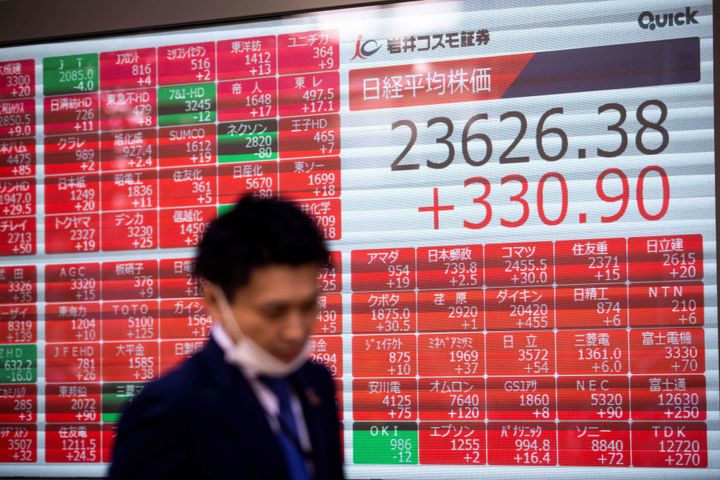 A man walks past an electronic board displaying the Nikkei 225 index and share prices on the Tokyo Stock Exchange in Tokyo on November 4, 2020, as Asian markets react to early predictions following the US presidential election. (Photo by Behrouz MEHRI / AFP) (Photo by BEHROUZ MEHRI/AFP via Getty Images)