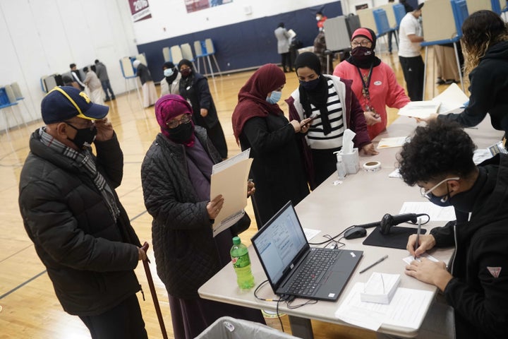 Dawleh Ahmed (second from left) and Naji Ahmed (left) wait in line to vote at Salina Elementary School on Nov. 3 in Dearborn, Michigan.