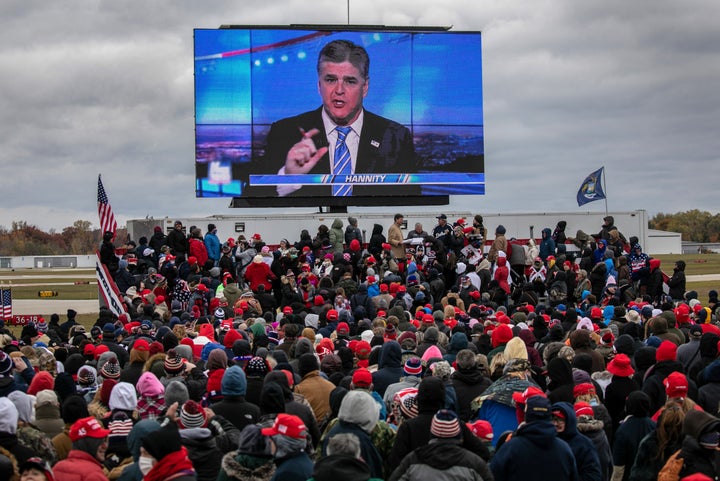 Supporters of President Donald Trump watched a video featuring one of his most vocal backers, Fox News host Sean Hannity, ahead of Trump's arrival to a campaign rally on Oct. 30 in Waterford, Michigan.