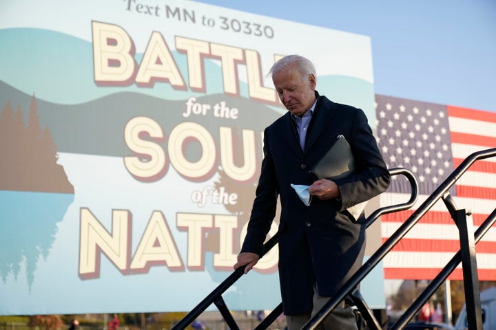 Democratic presidential candidate former Vice President Joe Biden holds his face mask after speaking at a rally at the Minnes