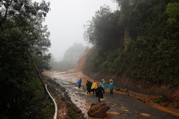 Workers walk around a road blocked by a landslide in San Cristobal Verapaz, Guatemala, on Saturday following Hurricane Eta. An estimated 100 people were believed to have been buried by a massive, rain-fueled landslide.