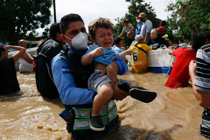 A toddler is carried over a flooded street in the aftermath of Hurricane Eta in Jerusalen, Honduras, on Thursday. The storm hit Nicaragua as a Category 4 hurricane on Tuesday.