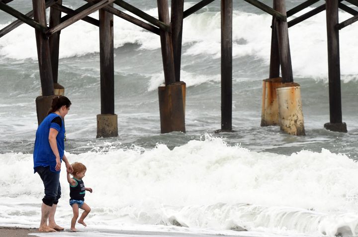 A mother lets her child play in the surf as heavy waves from Tropical Storm Eta come on the shore near the Cocoa Beach Pier in Florida on Saturday.