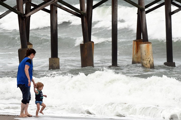 A mother lets her child play in the surf as heavy waves from Tropical Storm Eta come on the shore near the Cocoa Beach Pier in Florida on Saturday.