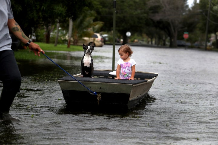 Lemay Acosta pulls his daughter Layla, 2, and dog Buster on a boat as they tour his flooded neighborhood in Plantation, Fla., on Monday.