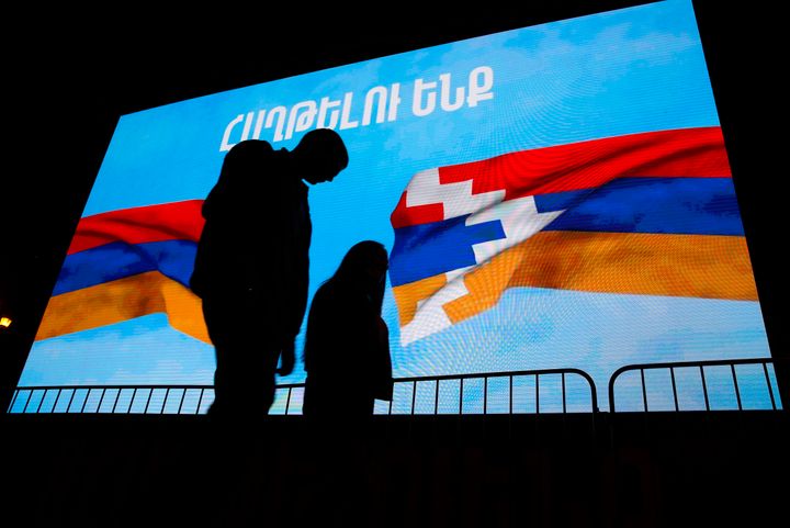 9 Νοεμβρίου 2020 - Ένα ζευγάρι περνάκάτω από μια οθόνη στην οποία εικονίζεται η σημαία της Αρμενίας (στ΄αριστερά) και η σημαία του Ναγκόρνο Καραμπάχ και τη φράση θα νικήσουμε.