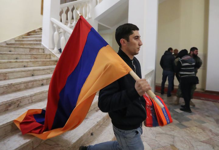 YEREVAN, ARMENIA - NOVEMBER 10, 2020: A man carries an Armenian flag after demonstrators protesting against the end of war in Nagorno Karabakh broke into the building housing the residence of the Armenian prime minister and government offices in capital Yerevan. On 10 November 2020, Armenia's prime minister Pashinyan, Russia's president Putin and Azerbaijan's president Aliyev signed an agreement to end the war in Nagorno Karabakh. Stanislav Krasilnikov/TASS (Photo by Stanislav Krasilnikov\TASS via Getty Images)
