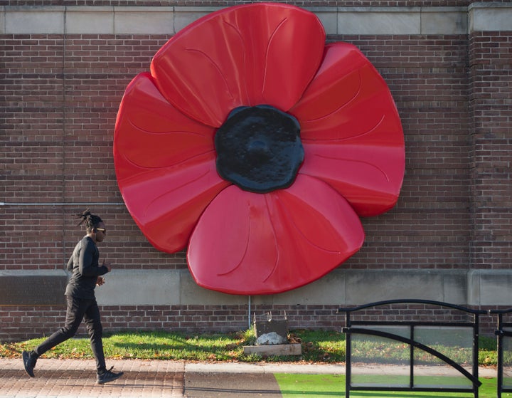 A man out for a run passes by the giant poppy on the front of Royal Canadian Legion, Branch 344, in Toronto, Ont. on Nov. 9, 2020.